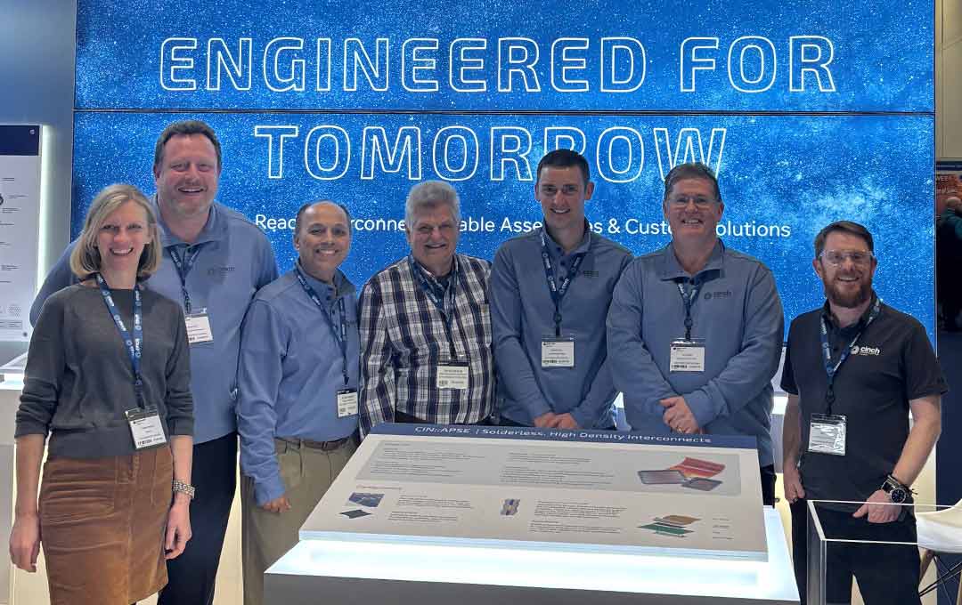 A group of Cinch employees at an event booth standing in front of a sign that reads Engineered for Tomorrow